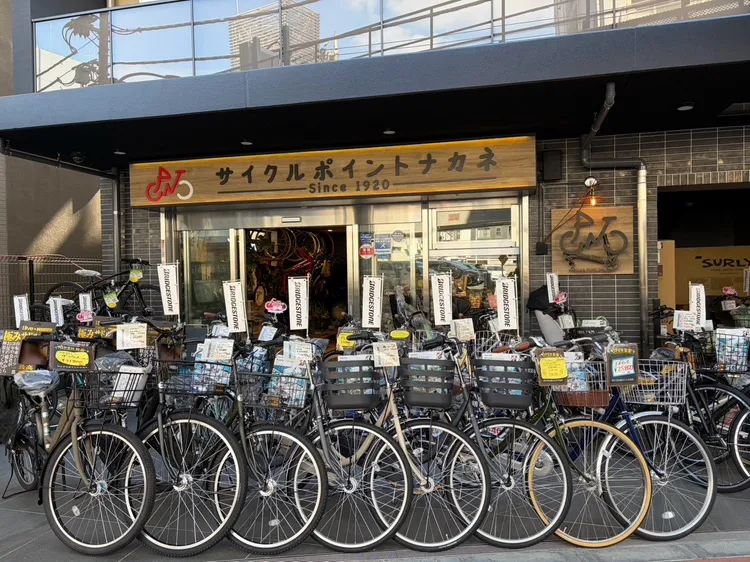 サイクルポイントナカネ山王店の店先。木の看板の下に自転車が並んでいる