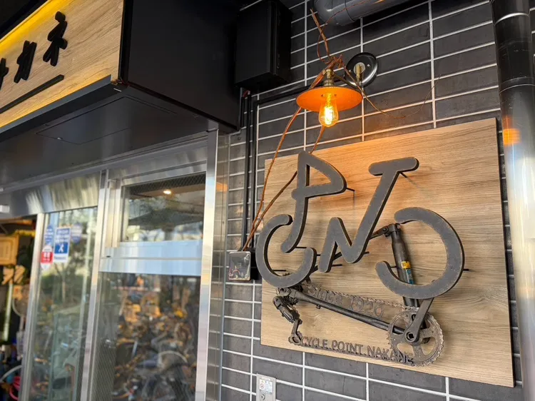 タイルの壁に掛かった、サイクルポイントナカネの鉄製看板